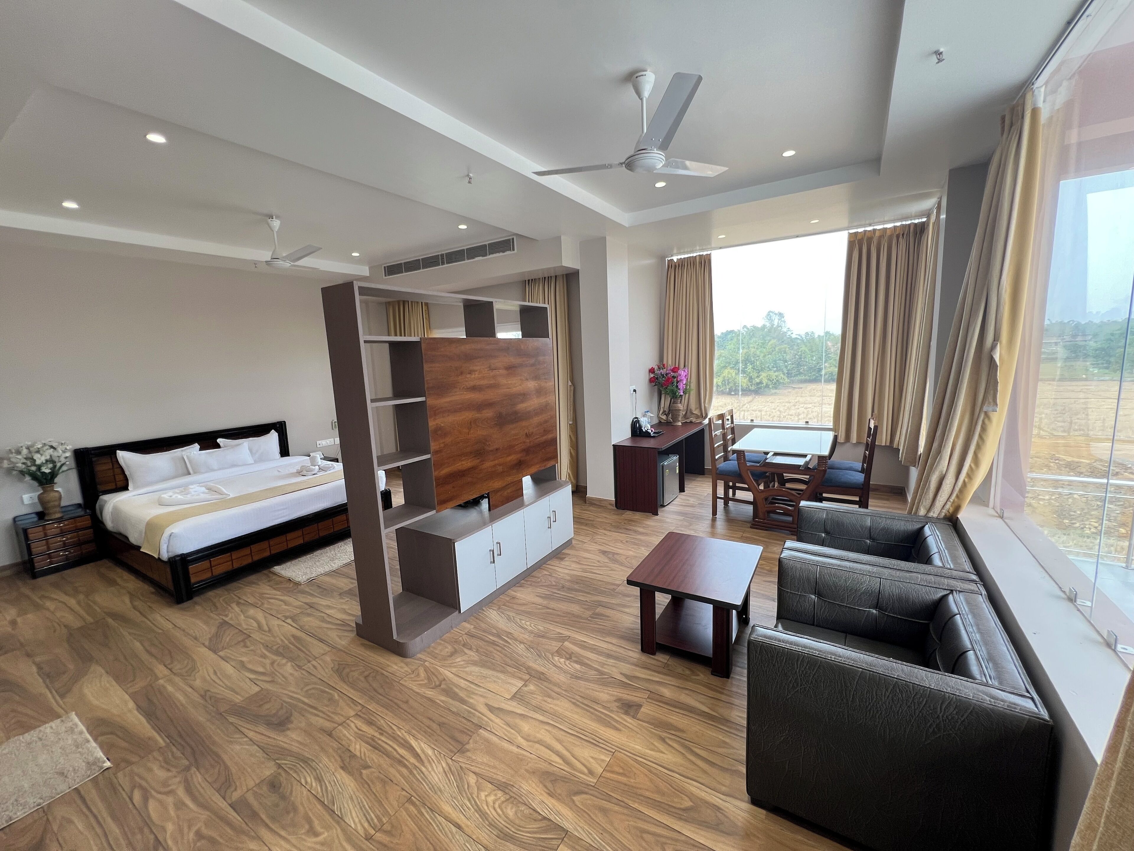 A modern hotel room with a bed, a TV unit, a dining area, and a sofa.