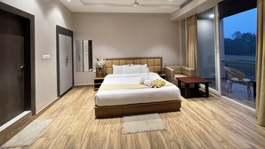 A modern hotel room with a large bed, a ceiling fan, a small table, a chair, and a view of the outdoors.