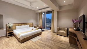 A modern hotel room with a large bed, a seating area, and a television.