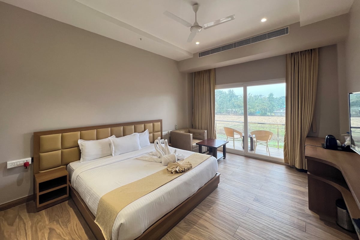 Une chambre d’hôtel avec un grand lit, un bureau, une chaise et un balcon avec vue.