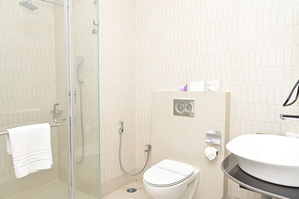A bathroom with a glass-enclosed shower, a toilet, and a sink. - Finns Weaver Resort Kaziranga (Bokakhat)