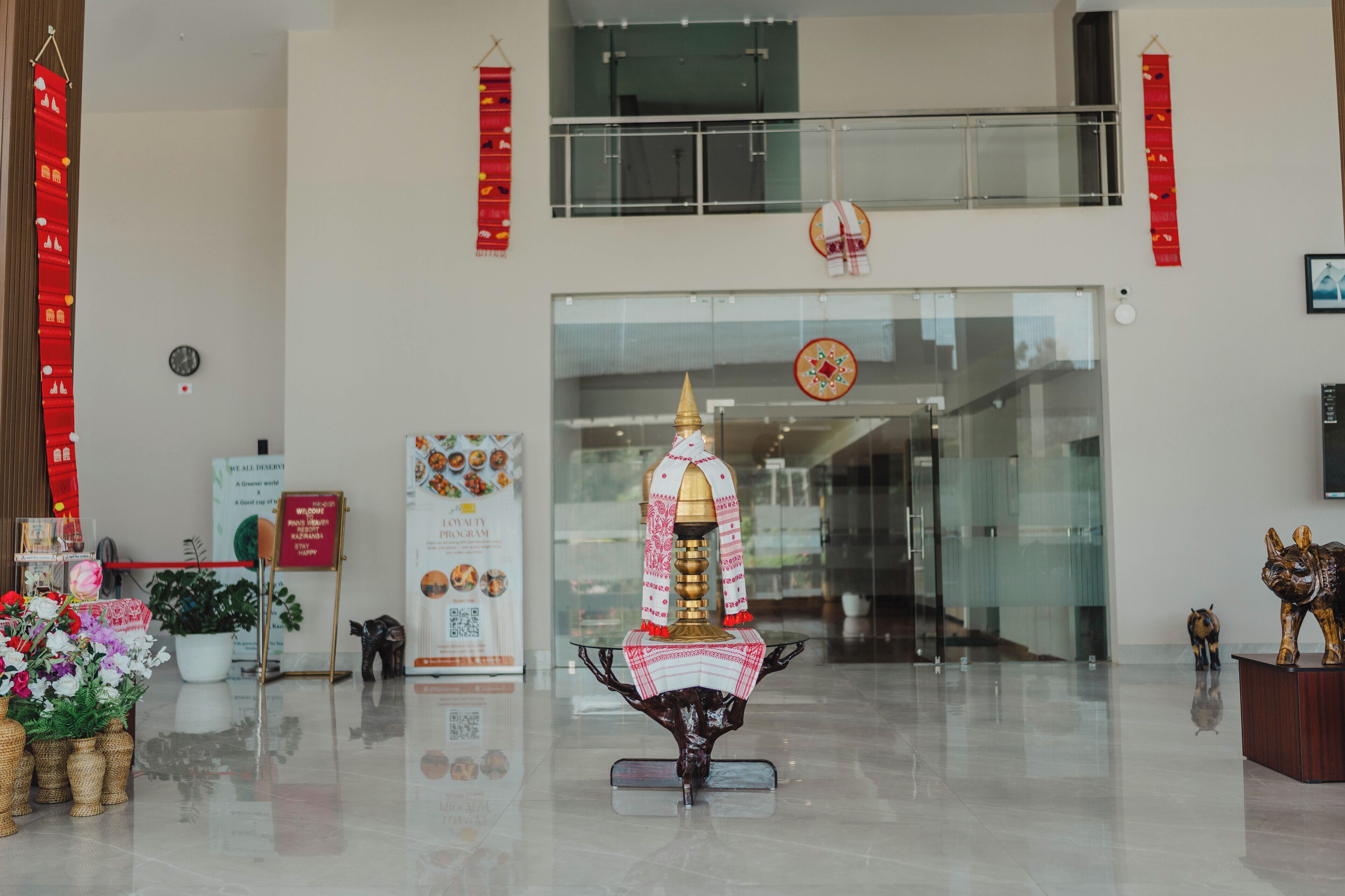 A lobby with a central decorative installation, a clock, and a glass entrance.