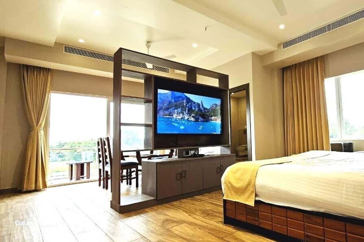Une chambre d’hôtel équipée d’un lit, d’une télévision, d’un bureau et offrant une vue sur l’extérieur.