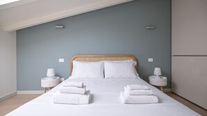 A neatly made bed with white linens and two pillows, flanked by two bedside tables with lamps, in a room with a sloped ceiling and light blue walls. - Volta 40 - A in Monza (Monza)