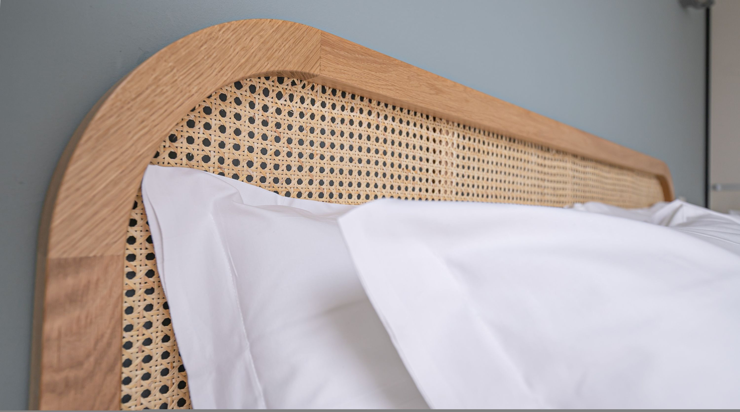 Una cama con cabecera de madera con diseño trenzado.