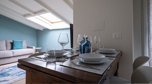 A dining area with a wooden table set for four, including plates, glasses, and cutlery. A blue vase and a white plate are on the table.