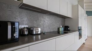 A modern kitchen with a stainless steel toaster, kettle, and coffee maker on the counter. - Volta 40 in Monza With 2 Bedrooms and 2 Bathrooms (Monza)