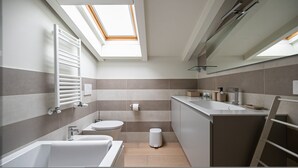 A modern bathroom with a skylight, a bathtub, a toilet, and a sink. - Volta 40 - B in Monza (Monza)