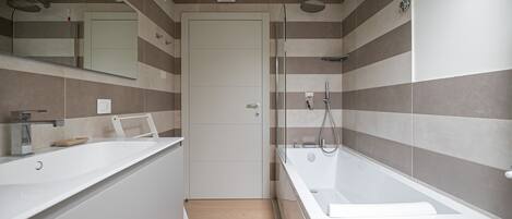 A modern bathroom with a shower, a bathtub, and a vanity with a mirror.