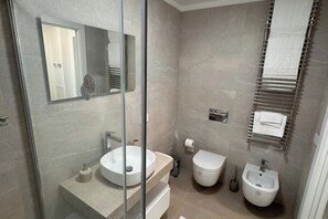 Een douche, een bidet, handdoeken, toiletpapier