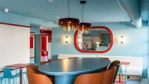 A modern conference room with a round table, orange chairs, and a red-framed mirror. - The Boc Hostels Beach (Palma de Mallorca)