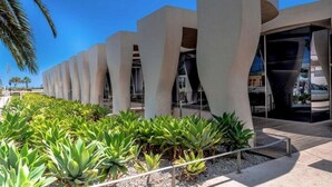 A modern building with a series of curved concrete structures and a garden with green plants.