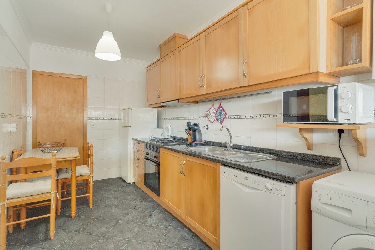 A kitchen with wooden cabinets, a microwave, a dishwasher, and a table with chairs.