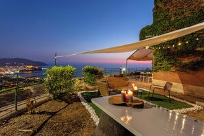 An outdoor terrace with a view of the city at dusk, featuring a table with candles, chairs, and a canopy. - House with sea view, with equipped garden, private parking, pets allowed (Agropoli)