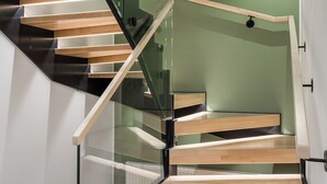 Een moderne trap met glazen leuning en houten treden.
