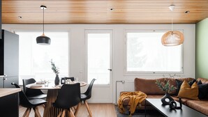 Een moderne woonkamer met een eethoek, houten plafond en grote ramen.