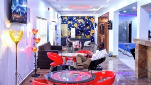 A modern lounge area with a TV, comfortable seating, and a decorative wall. - G- throne Hotel and Suites (Port Harcourt)