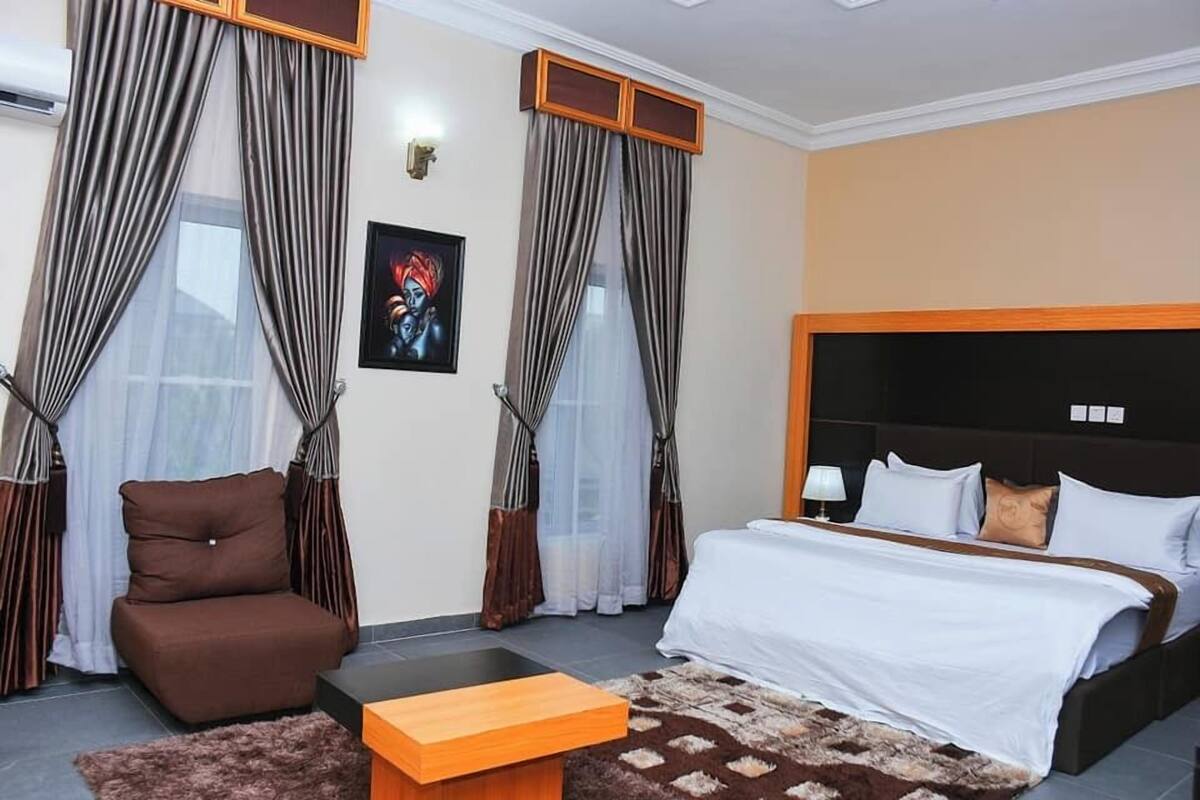 Ein Hotelzimmer mit Bett, Sofa, kleinem Tisch und Vorhängen.