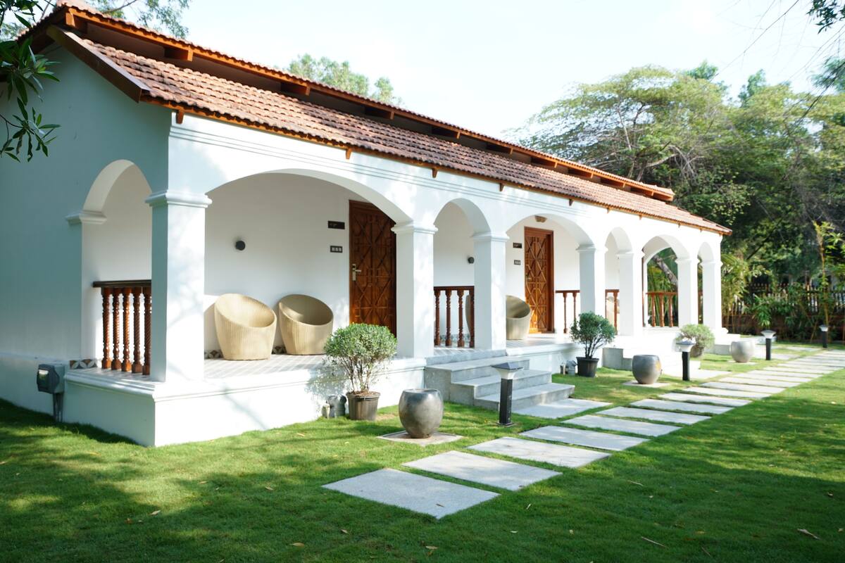 A white building with a tiled roof, multiple arches, and a paved pathway leading to the entrance.