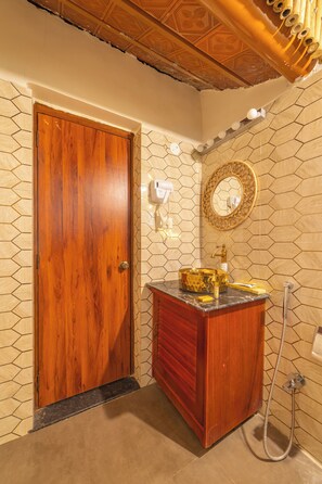 A bathroom with a wooden door, a vanity with a gold sink, a mirror, and a shower. - Brown Town Resort & Spa (Hyderabad)