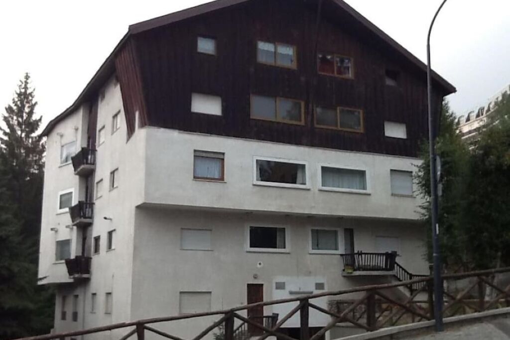 Un immeuble à plusieurs étages, dont les façades sont composées d’un mélange de bois clair et foncé, agrémenté de balcons et d’un escalier menant à l’entrée.