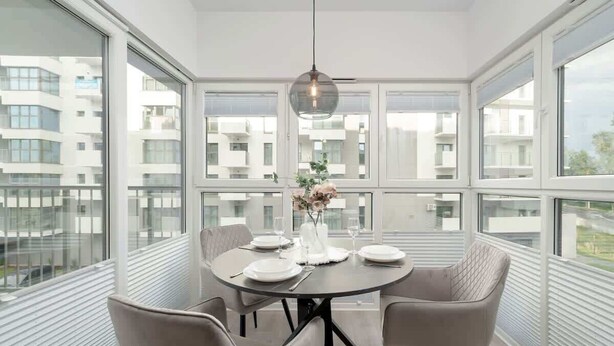 Un comedor moderno con una mesa redonda para cuatro personas, ventanas amplias y vistas a la ciudad.