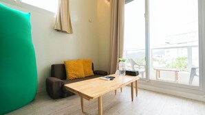 Una habitación acogedora con un sofá, una mesa de madera y vistas al exterior.
