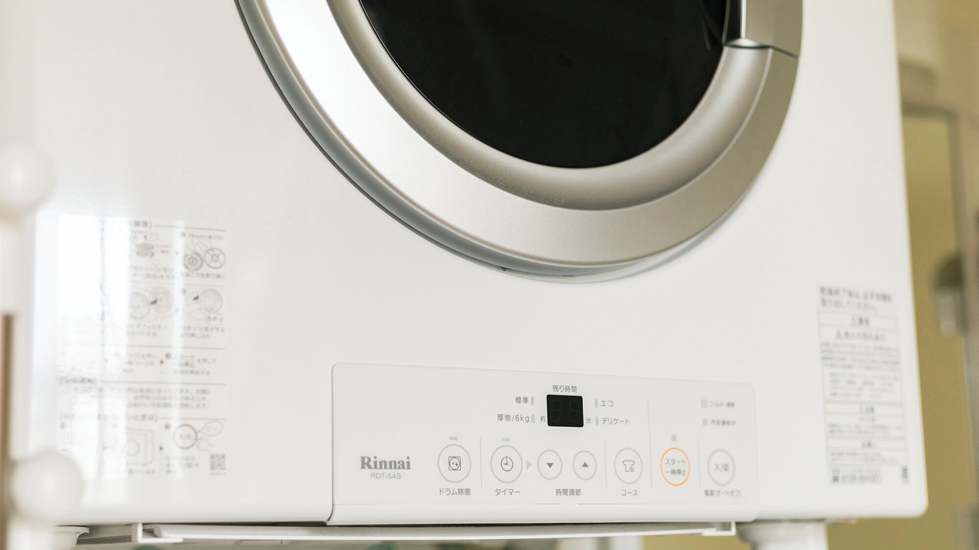 A front view of a white Rinmai RO-54S washing machine with control panel and instruction manual.