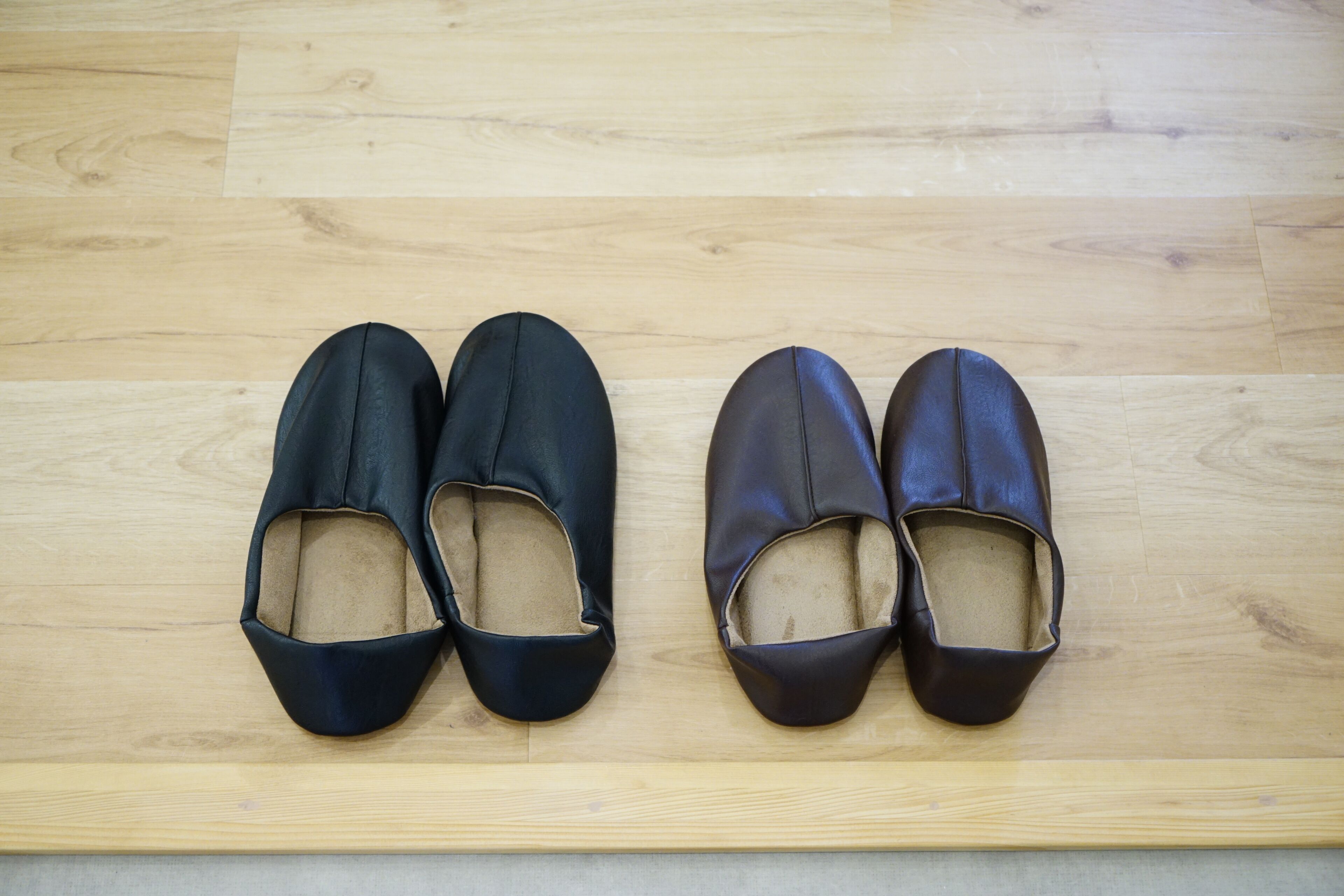 A pair of black and brown shoes on a wooden floor.