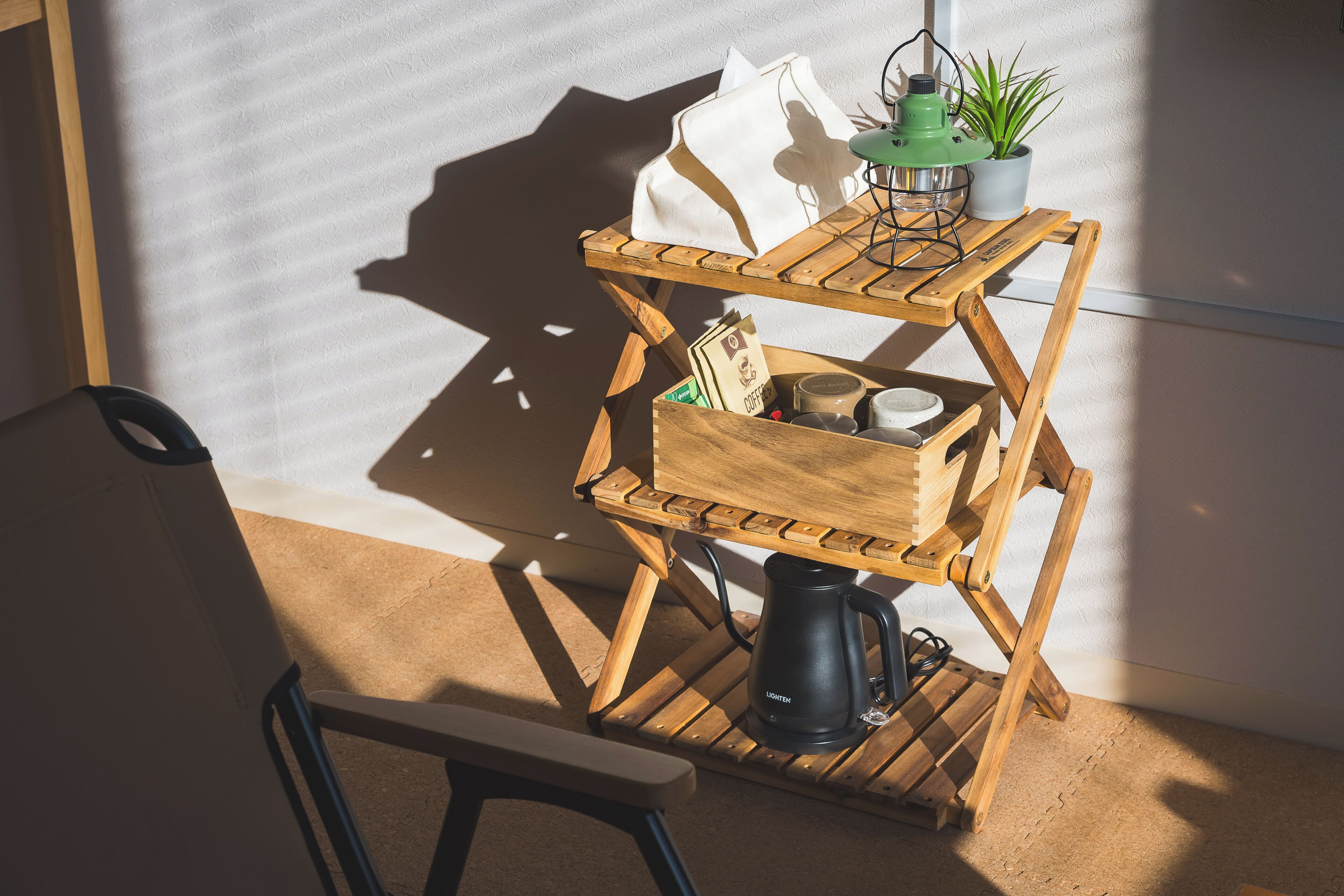 A wooden coffee station with a kettle, a plant, and a white bag.