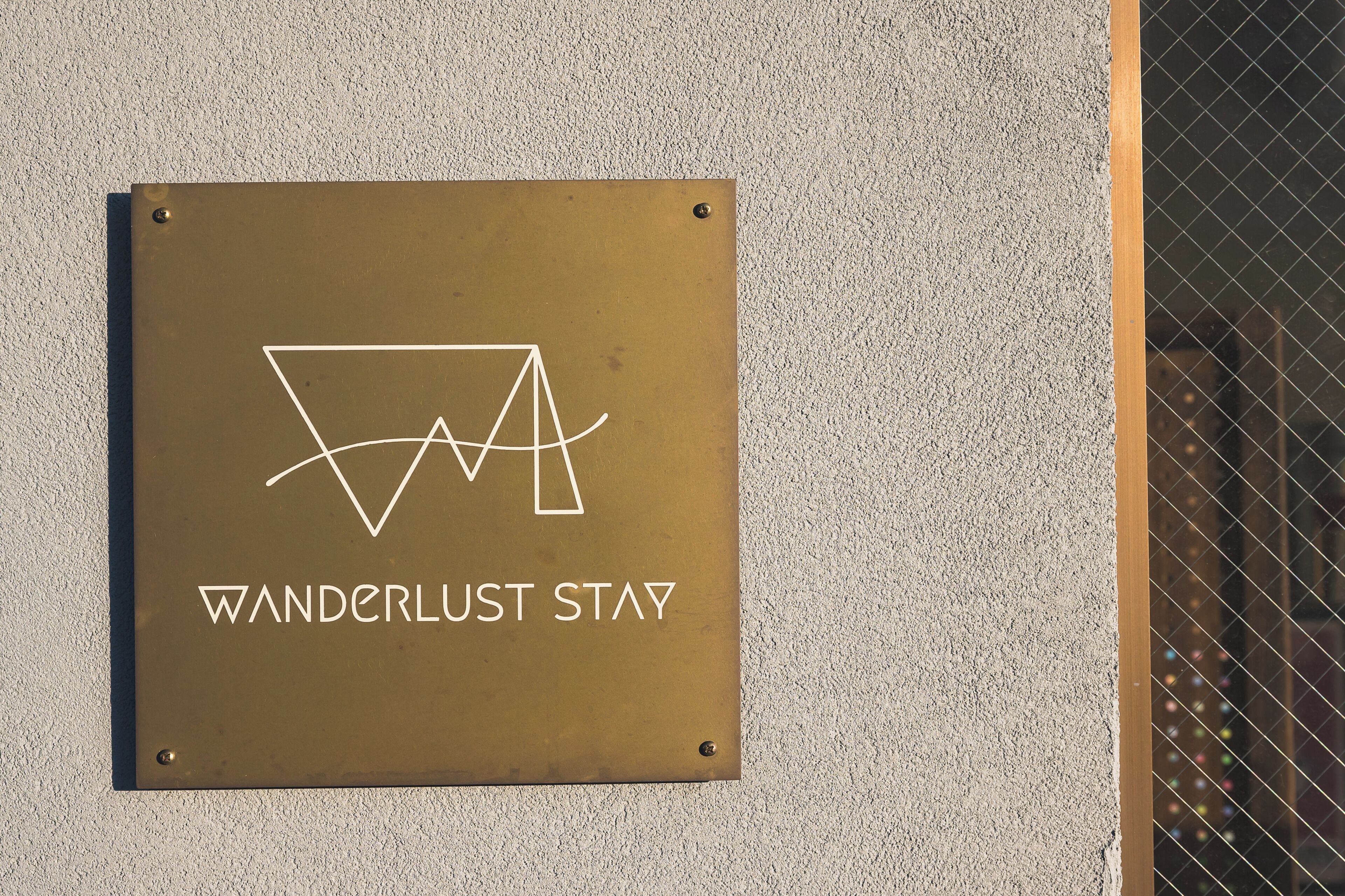A sign with the text 'WANDERLUST STAY' and a stylized logo.