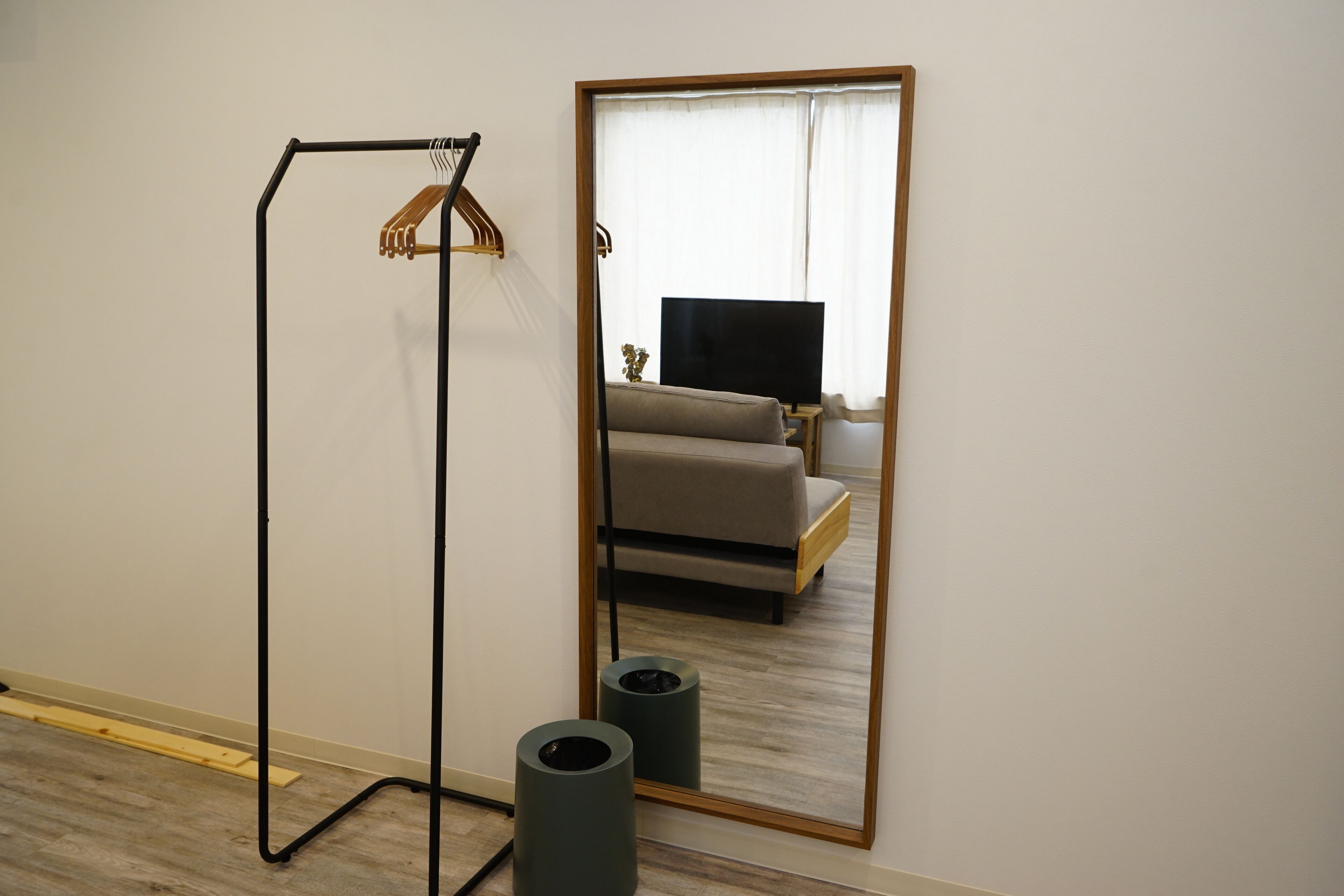 A room with a mirror, a standing fan, and a sofa.