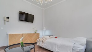Ein modernes Hotelzimmer mit Bett, Fernseher, Schreibtisch und Stuhl.