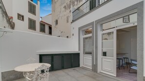 Ein Innenhof mit rundem Tisch und Stühlen, einer Schiebetür und einer Treppe, die zu einer oberen Ebene führt.