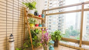 A balcony with a wooden shelf holding potted plants, a vase with flowers, and a lighthouse decoration. - Muchun Apartment (Guangzhou)