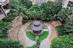 Une cour circulaire avec un kiosque central, entourée d’une végétation luxuriante et de palmiers.