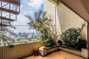 A balcony with tiled flooring, potted plants, and a red stool. - Muchun Apartment (Guangzhou)