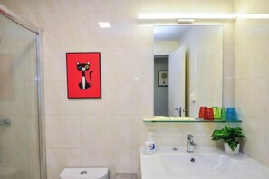 Un baño con inodoro, lavamanos, espejo y un cuadro en la pared.