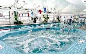 Ein Innenpool mit Whirlpool, klarem Wasser und Sicherheitsschildern.