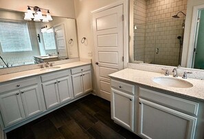 Une salle de bain avec deux lavabos, un grand miroir et un espace douche.