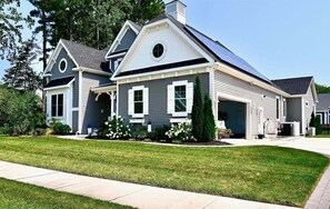 Ein zweigeschossiges Haus mit Garage, einer überdachten Veranda und einer Solaranlage auf dem Dach.