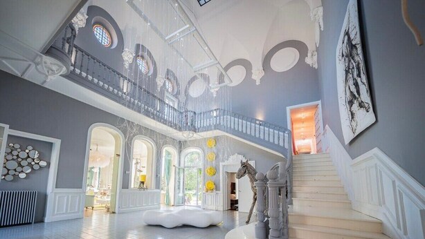 A spacious interior with a grand staircase, multiple levels, and a central seating area.