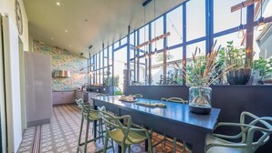 A modern kitchen with a large island, bar stools, and a view through large windows.