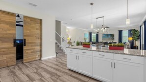 Eine moderne Küche mit weißen Schränken, Granit-Arbeitsplatten und Pendelleuchten.