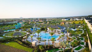Ein Resort mit mehreren Schwimmbecken, Palmen und einem Golfplatz.