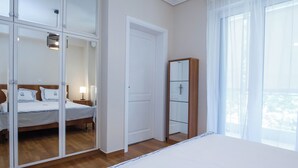 Een slaapkamer met een bed, een kledingkast, een spiegel en een deur.