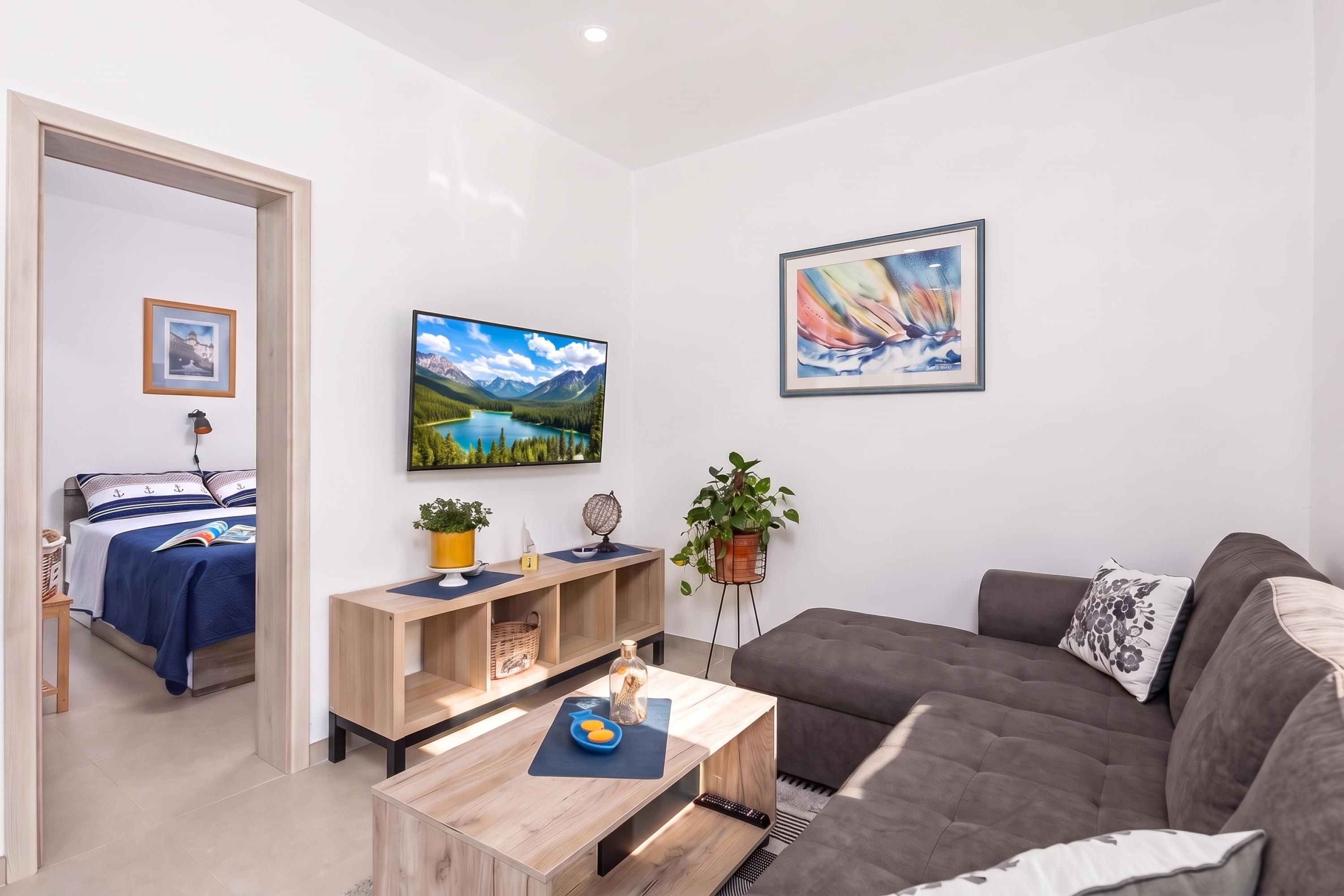 Un salón moderno con sofá, mesa de centro, televisor y cama con vistas al exterior.