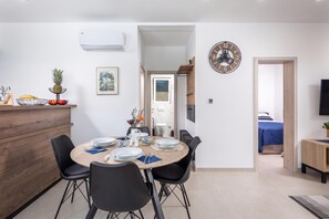 A modern dining area with a round table set for four, black chairs, and a white air conditioning unit above. - Holiday Home Sole (Kostrena)