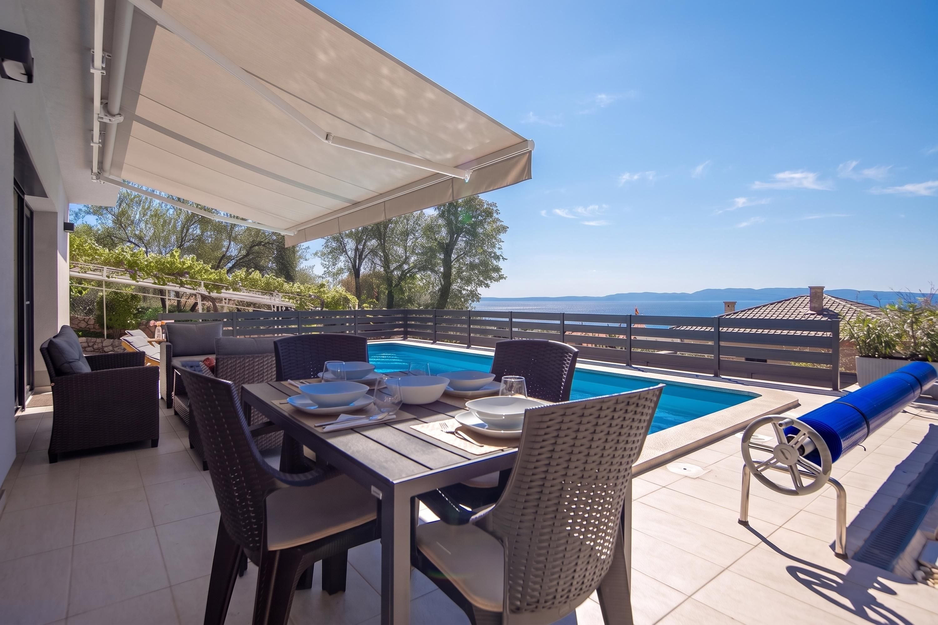 An outdoor dining area with a pool, overlooking a scenic landscape.