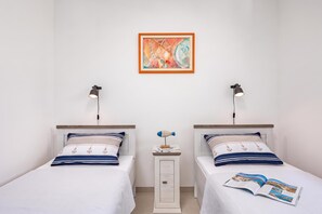 Una habitación con dos camas, una mesita de noche con lámpara y un cuadro abstracto enmarcado en la pared.